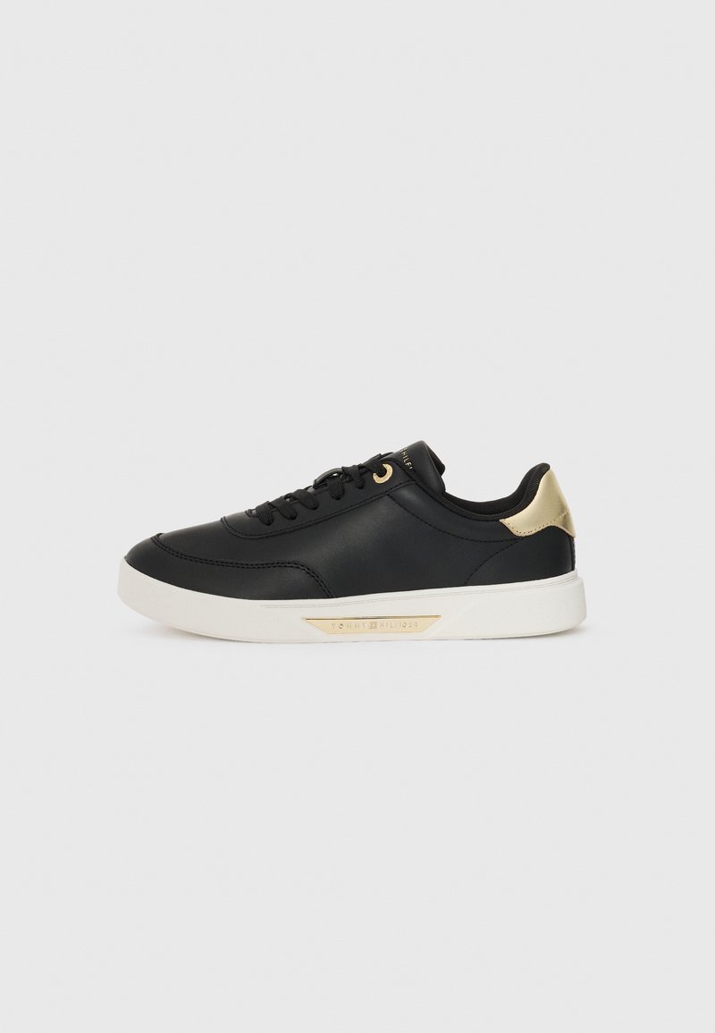 Black leather sneaker with a smooth texture, white rubber sole, gold accents on the heel and eyelets, featuring a logo on the side.
