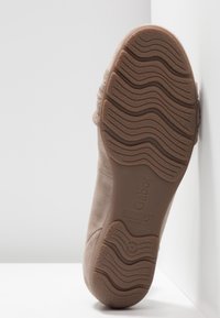 Chaussure en suede beige avec une semelle en caoutchouc texturé, présentant un motif ondulé, une semelle intérieure rembourrée et des détails de design minimalistes. Marque Gabor visible.