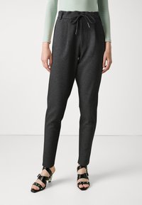 Pantalons jogger tissés gris avec taille élastique, d�étail à cordon, jambes fuselées, associés à des sandales noires à lanières avec des talons épais.