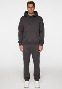 Grå hoodie och sweatpants set i mjukt tyg. Hoodien har en framficka, dragsko och ribbade muddar; byxorna har elastiska fållar.