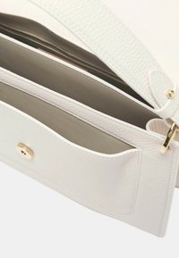 Interno di una borsa a mano bianca in pelle con finitura testurizzata, una tasca con zip e dettagli in hardware color oro.