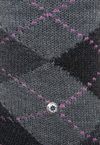 Accesorio de punto en gris oscuro con un patrón de diamantes, con detalles en rosa y un logo circular plateado adjunto. Acabado texturizado.