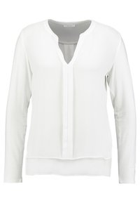 Blusa bianca a maniche lunghe con scollatura a V e placca senza bottoni. Tessuto morbido e liscio con un dettaglio a strati all'orlo inferiore.