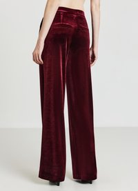 Weinrote Samt-Hose mit weitem Bein und glatter Textur, mit mittelhohem Bund und Gesäßtaschen. Dezenter Glanz verleiht dem Stoff eine elegante Note.
