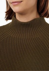 Strickpullover mit hohem, geripptem Kragen in einem satten Olivgrün. Die Textur ist dick und bietet eine enge Passform am Hals.