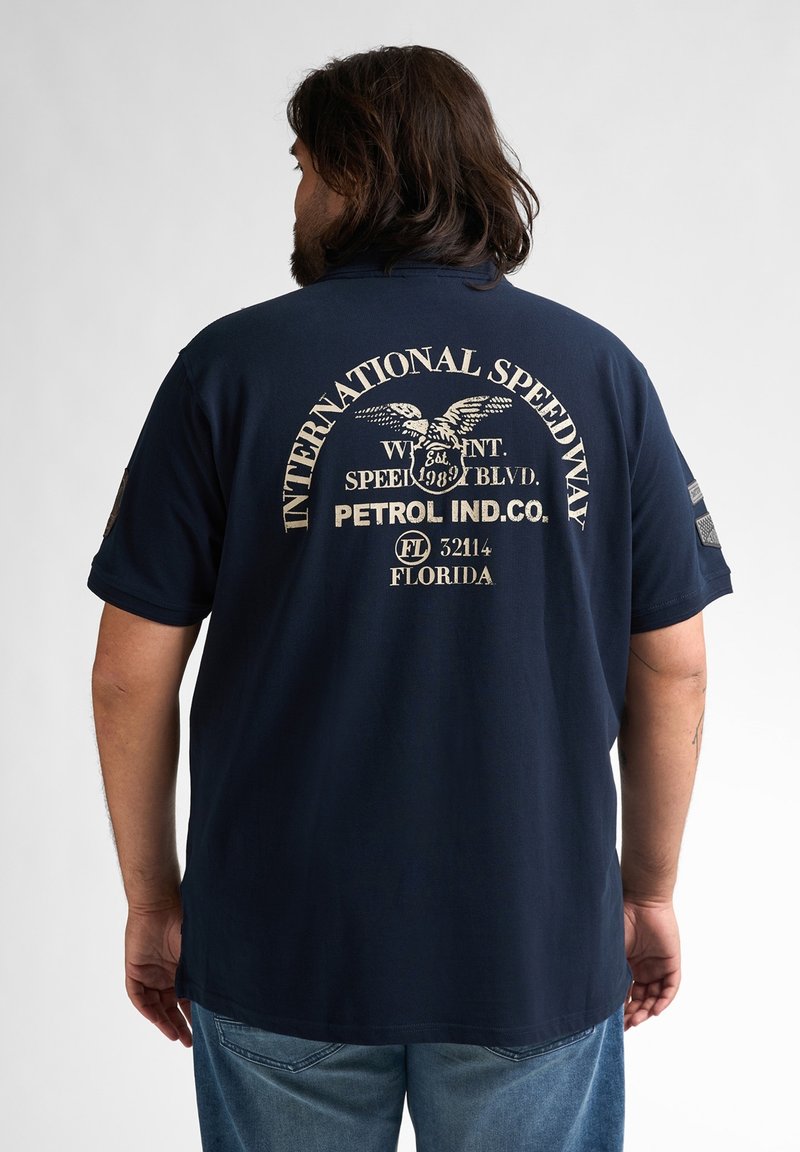 Mörkblå bomulls t-shirt med en stor vit grafisk tryck på baksidan, där det står "INTERNATIONAL SPEEDWAY" och en örn-design.