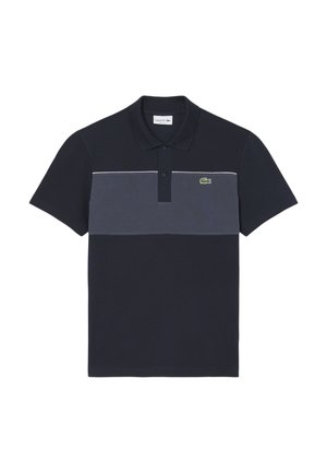 Polo blu navy con una fascia orizzontale grigia. Presenta un colletto classico, maniche corte e un piccolo logo verde a forma di coccodrillo sul petto.