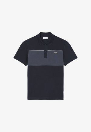 Polo blu navy con una fascia orizzontale grigia. Presenta un colletto classico, maniche corte e un piccolo logo verde a forma di coccodrillo sul petto.