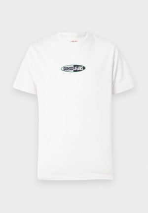 Fehér pamut póló rövid ujjakkal és kerek nyakkivágással. Középen egy hímzett, "GUESS JEANS" feliratú logó látható.