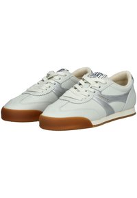 Bílé kožené tenisky se stříbrnými akcenty, kulatá špička, plochá hnědá gumová podrážka a šněrování vpředu. Obsahují polstrovaný límec a měkký interiér.