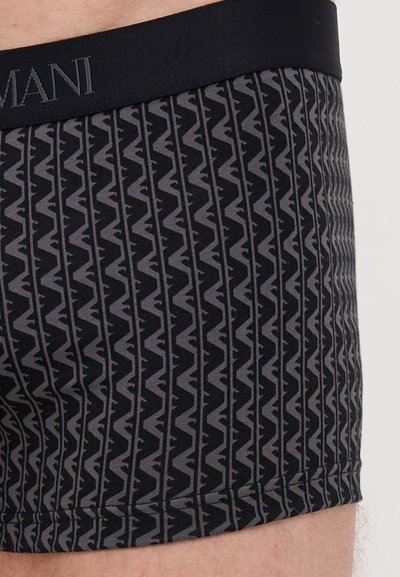 Black boxer briefs with a zigzag pattern in dark gray. The waistband features the brand name in a contrasting color. Smooth fabric texture.