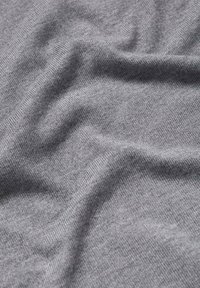 Tissu tricoté gris doux avec des plis subtils et une texture, montrant un tissage fin et une surface lisse.