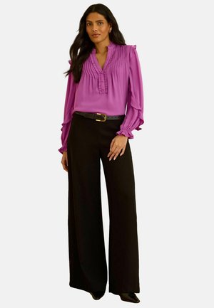 Fuchsia blouse with pleated details, ruffled sleeves, and a v-neck, paired with high-waisted black wide-leg trousers and a black belt.