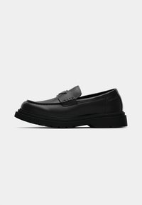 Sort læder loafer med rund tå og stikninger, der har en tyk gummisål og et minimalistisk design.