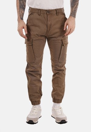 Pantaloni cargo in un tessuto marrone con una finitura leggermente strutturata. Presentano diverse tasche laterali e polsini elasticizzati. Chiusura con bottone frontale.