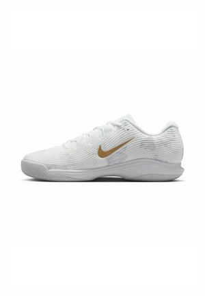 Witte sportieve schoen met een gestructureerde bovenkant, voorzien van een gouden Nike swoosh, vetersluiting, ronde neus en een flexibele rubberen zool.