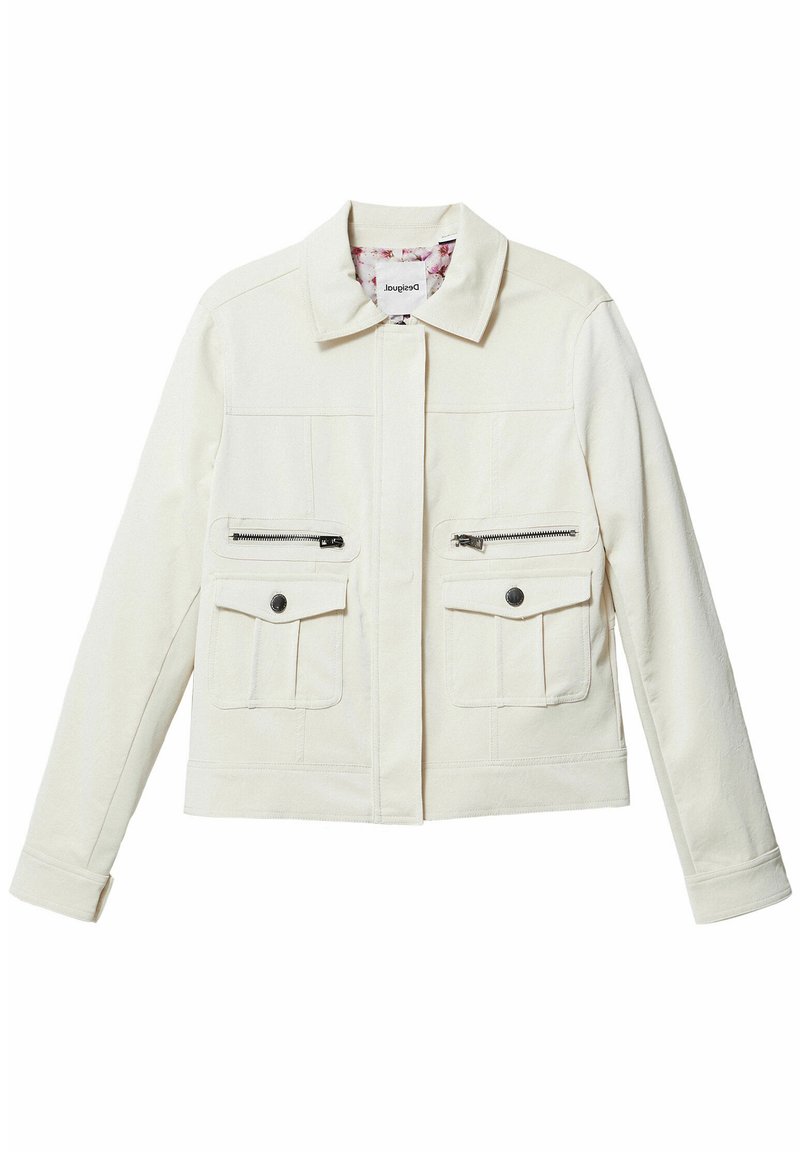 Crème-jack met spitse kraag, voorrits verborgen achter een klep, twee met rits afsluitbare borstzakken en twee met knopen sluitende onderzakken.