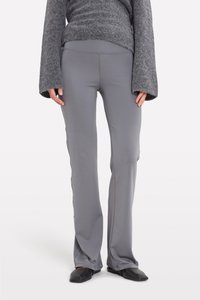 Gray, fitted athletic pants with a smooth texture, flared bottom, and side seam detailing. Worn with a gray sweater and black flats.