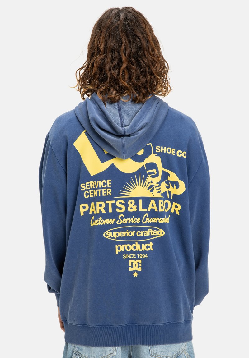 Modrá mikina s kapucňou so zmäkčeným povrchom. Na zadnej strane sú žlté grafické texty a obrázky. Vyrobená z mäkkej tkaniny, s dlhými rukávmi.