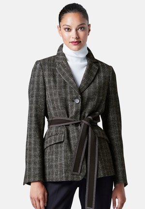 Veste tissée en noir et blanc avec un motif à carreaux, à un bouton, deux poches avant, taille ceinturée et col évasé.