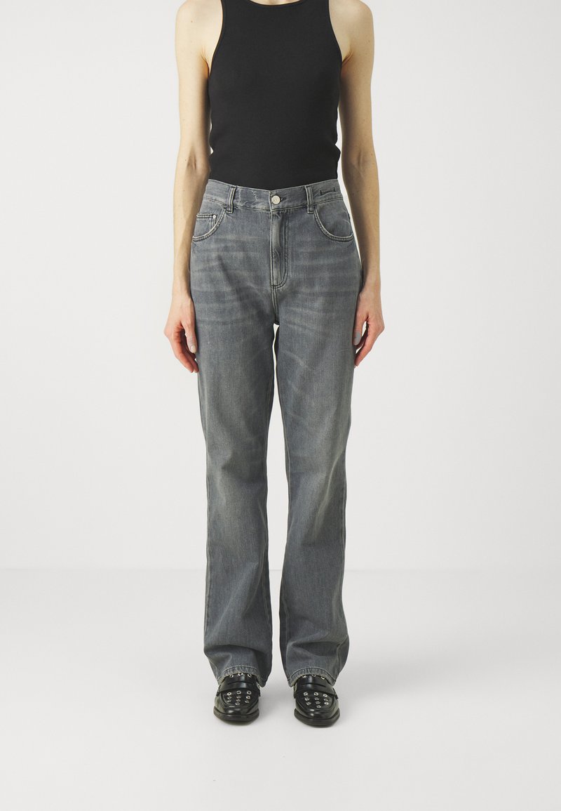 Gray denim jeans with a high waist, straight leg, and two front pockets, paired with a black tank top and black studded shoes.