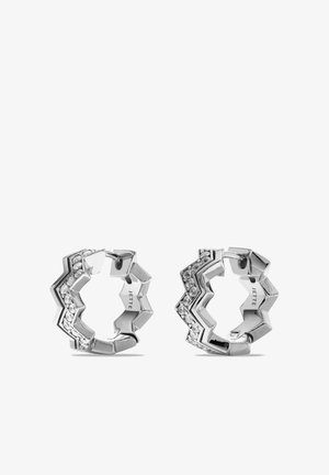 Orecchini a cerchio a zigzag in argento con cristalli trasparenti incastonati e nome del marchio inciso sulla superficie interna, mostrati su sfondo bianco.