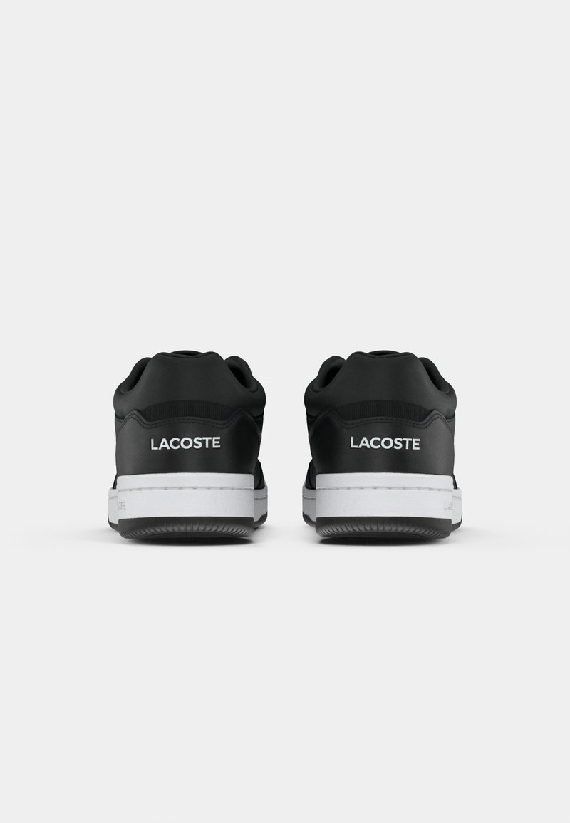 Baskets Lacoste noires avec un dessus lisse, des accents blancs, un col rembourré et une semelle en caoutchouc texturé, vues de dos.