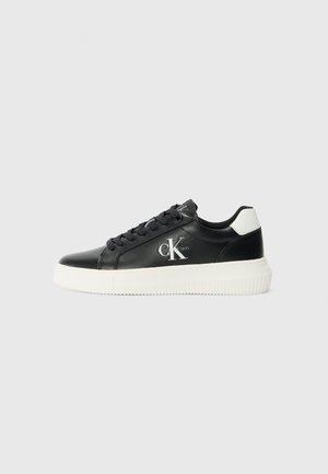 Czarny, skórzany sneaker typu low-top z białą podeszwą i zakładką na pięcie, z logo Calvin Klein "cK" po boku i czarnymi sznurowadłami.