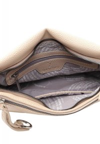 Intérieur d'un sac en cuir beige avec une poche zippée et une doublure douce à motifs en gris clair avec du texte. Les accents incluent un anneau en métal argenté.