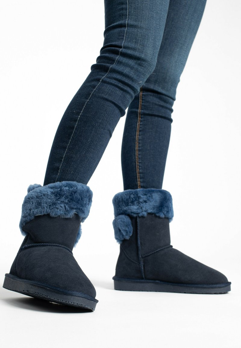 Stivali alla caviglia in suede blu navy con un soffice e texture blu in pelliccia sintetica, con punta arrotondata e suola piatta.
