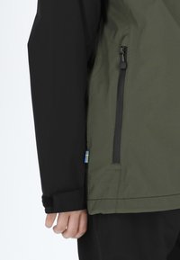 Green and black waterproof jacket with a soft texture, featuring a side zipper and a small Swedish flag accent at the hem.
