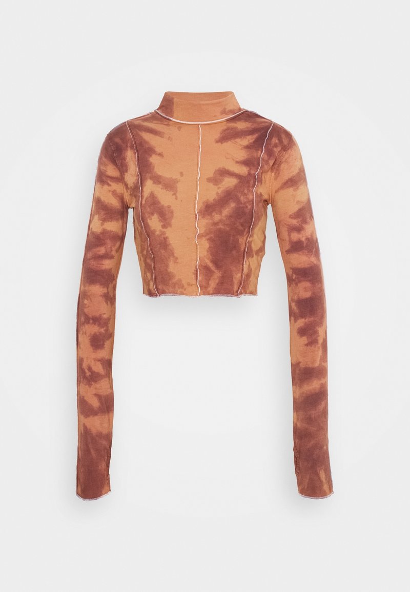 Långärmad, kort turtleneck-top med brun och beige tie-dye-mönster samt synlig vit sömnad på en enfärgad bakgrund.
