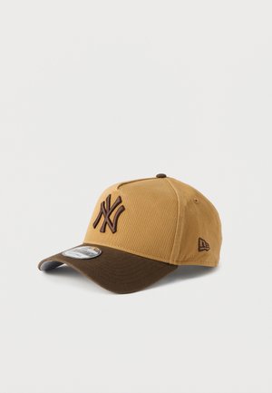 Brun och beige basebollkeps av tyg med en böjd skärm och broderad logotyp framtill. Har en kontrasterande brun skärm.