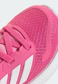 Baskets de sport rose vif avec tige en maille, lacets texturés et accents blancs. Présentent un design de soutien et une semelle en caoutchouc pour une meilleure adhérence.