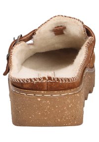 Brązowy zamszowy but wsuwany z puszystą podszewką, grubą korkową podeszwą, kontrastowym przeszyciem i akcentem w postaci klamry z boku.