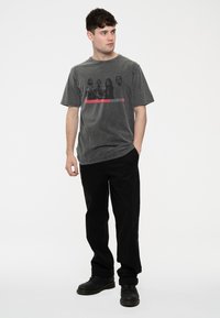 Gray cotton t-shirt featuring a graphic print of four figures and "Killers" text in red, paired with black pants and boots.
