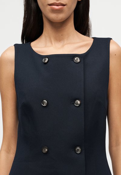 Σκούρο ναυτικό μπλε αμάνικο φόρεμα με τετράγωνη λαιμόκοψη και διπλό κούμπωμα με αντίθετα κουμπιά, κατασκευασμένο από λείο ύφασμα.