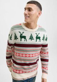 Maglione lavorato a maglia con base crema, renne e alberi verdi, strisce orizzontali rosse e blu navy e motivi di fiocchi di neve. Collo e polsini a coste.