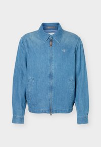 Ανοιχτό μπλε τζιν μπουφάν με φερμουάρ μπροστά, δύο λοξές πλαϊνές τσέπες, μυτερό γιακά και μικρό κεντητό λογότυπο στο στήθος.