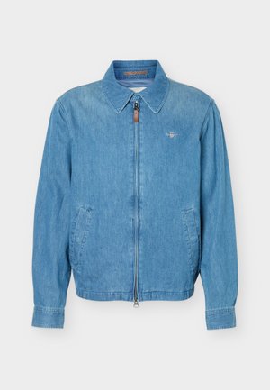 Hele sinine teksajakk esiosal lukuga, kahe kaldu küljetaskuga, terava kraega ja väikese tikitud logoga rinnal.