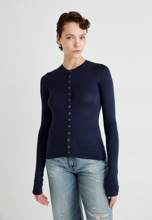 Navy long-sleeve button-up top made from a soft material, featuring a fitted design, round neck, and subtle button embellishments.