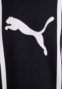 Fekete pulóver, amelyen egy nagy, fehér Puma logo látható, amely egy ugró macskát formáz. Az anyag sima, kötött textúrájú.