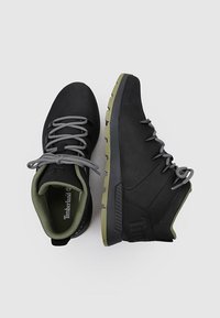 Botas de senderismo negras con cordones grises y acentos verdes. Suela de goma texturizada, cuello acolchado y un diseño estructurado para mayor soporte.