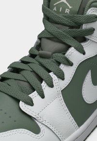 Κοντινή λήψη πράσινου και λευκού αθλητικού παπουτσιού Nike Air με υφασμένες πράσινες κορδόνια δεμένες πάνω σε επενδεδυμένη γλώσσα.