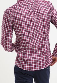 Rood en marineblauw geruite overhemd met lange mouwen, kraag en een plooi aan de achterkant. Gladde katoenen stof met een ontspannen pasvorm.