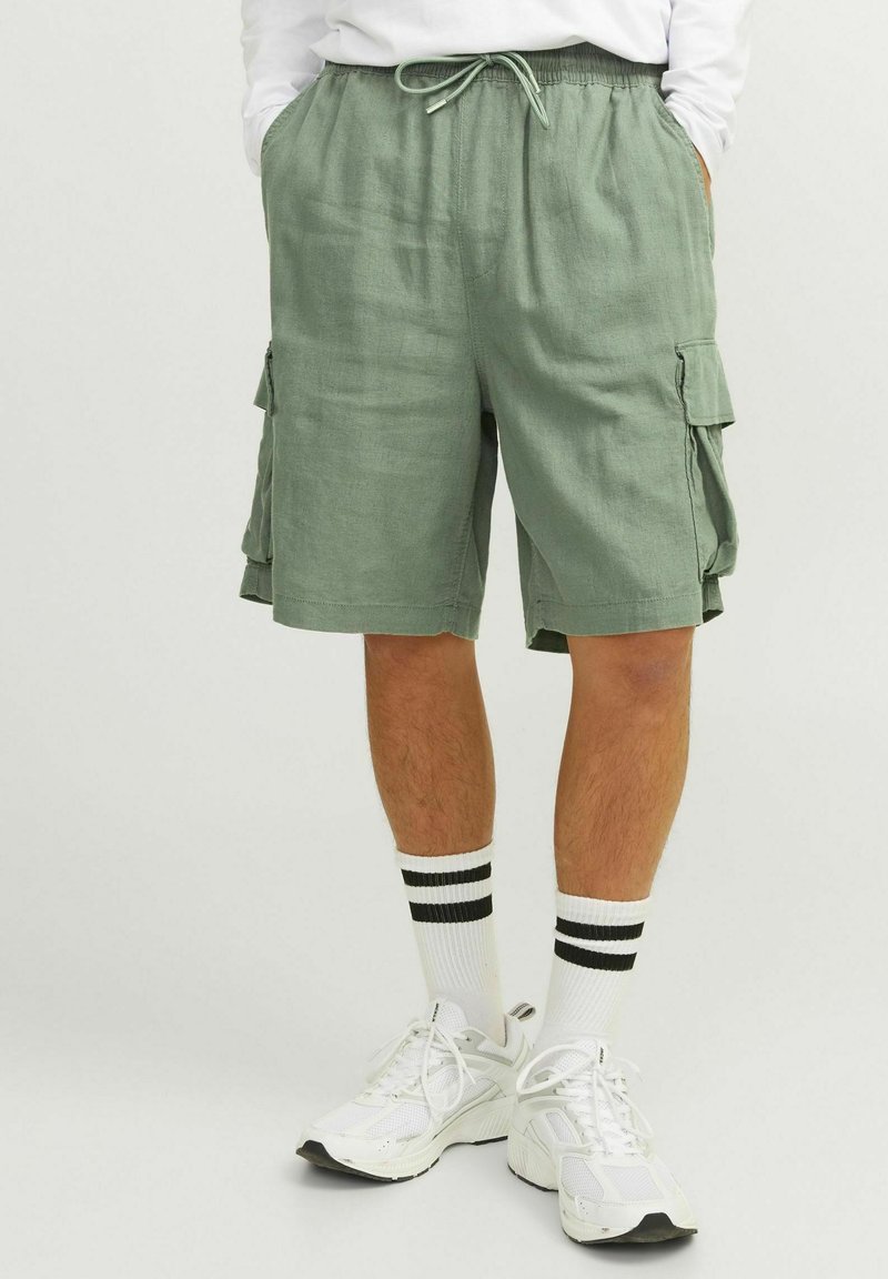 Shorts cargo verts avec une taille élastique et un cordon de serrage. Comprend deux poches latérales et deux poches à rabat sur les jambes. Design décontracté.
