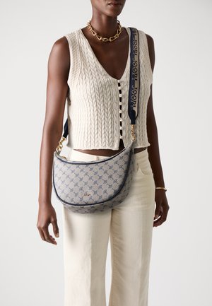 Borsa hobo in tessuto blu chiaro con motivo geometrico, dotata di una tracolla blu navy con branding, accessori in oro e una forma curvata.