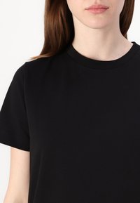 Svart bomulls t-skjorte med klassisk rund hals og korte ermer; glatt tekstur med minimal søm og ingen synlige logoer eller mønstre.