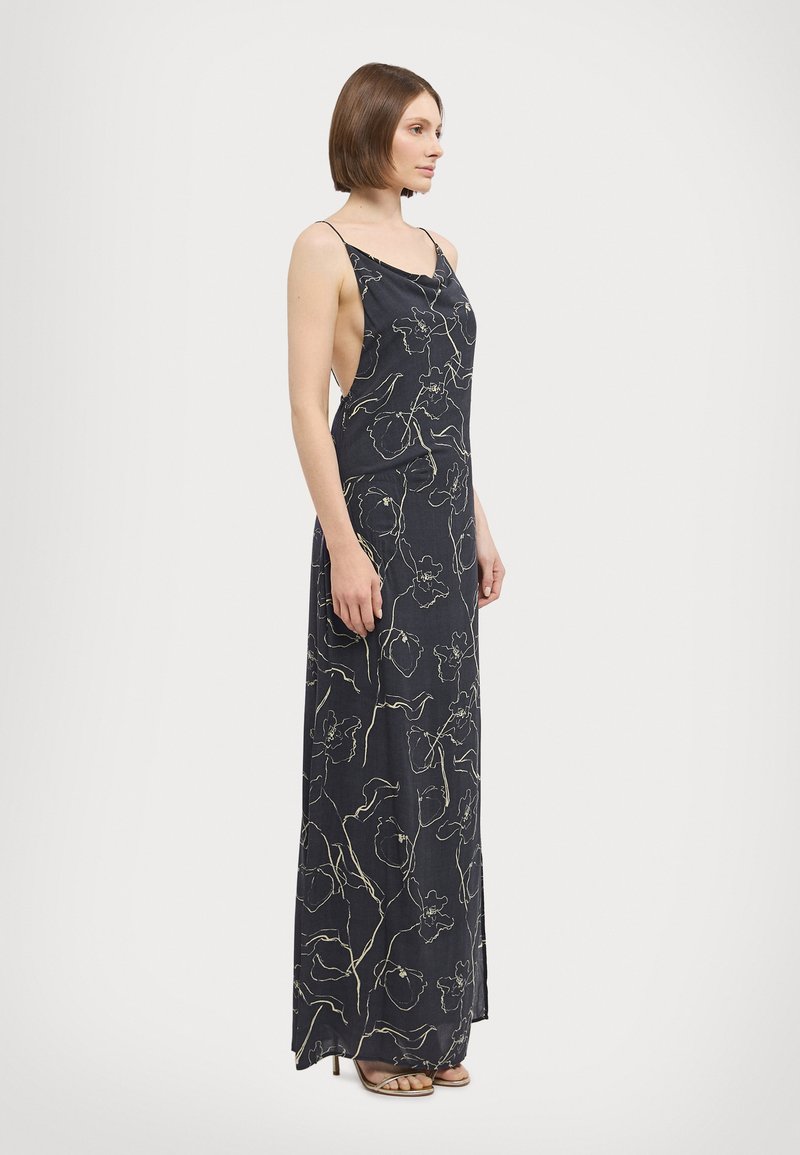 Robe maxi en tissu bleu marine foncé présentant un motif floral beige clair. Conçue avec des fines bretelles et une silhouette décontractée.