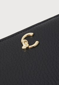 Black textured leather with a gold-tone clasp featuring a curved design and linked detail, providing a sleek and contemporary look.